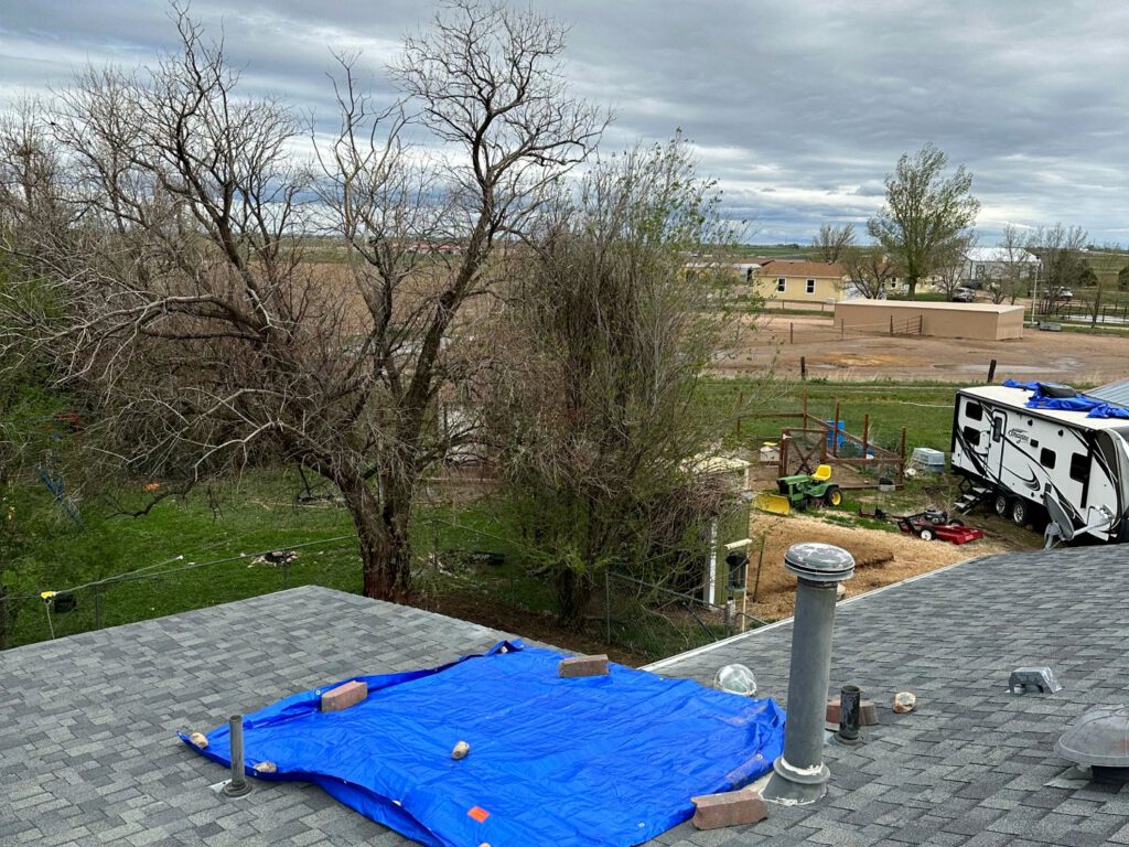 A tarp weighted down over a damaged section of shingle roof