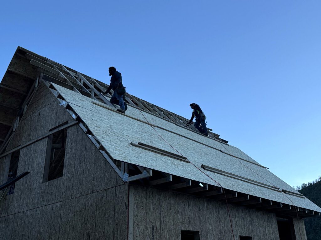 Roofing crew working on a new roof deck under a clear sky