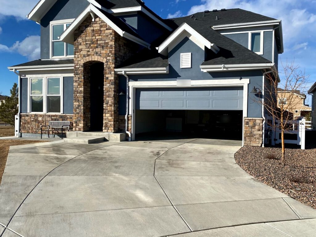 A finished architectural shingle roof on a two-story stone-front home