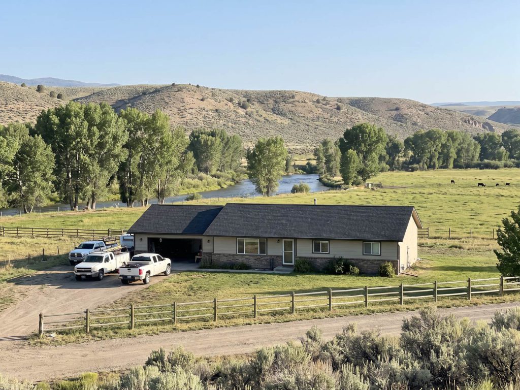 Ranch house with a new roof in a green river valley with sagebrush hills