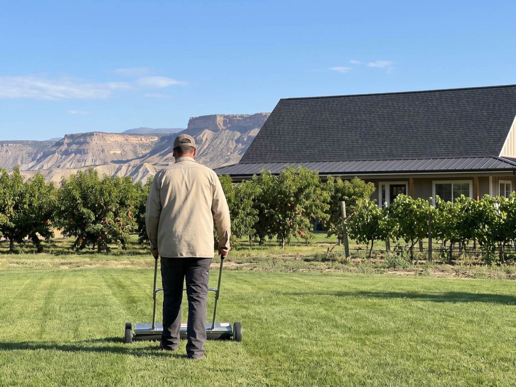 Worker sweeping for nails beside a newly roofed farmhouse and peach orchard
