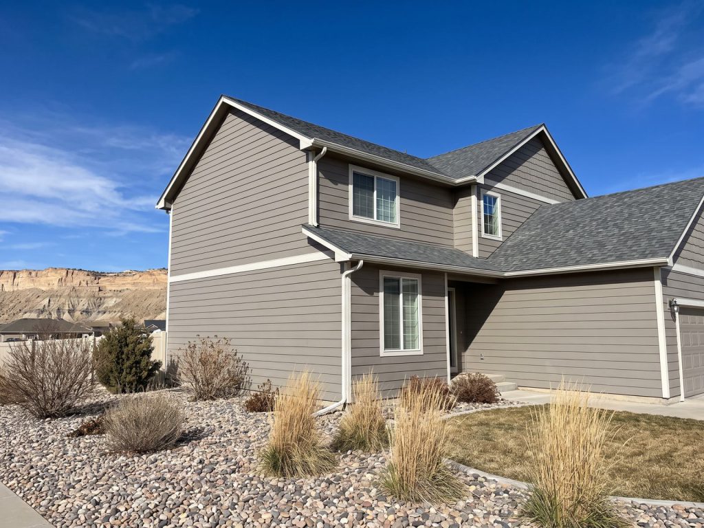 Two-story home with new gray lap siding and white trim under a blue Colorado sky